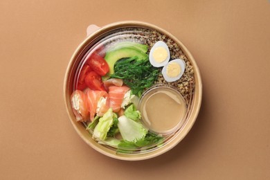 Tasty food in container on beige background, top view