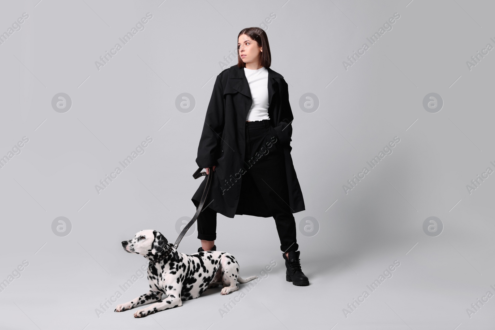 Photo of Beautiful young woman with her adorable Dalmatian dog on light grey background. Lovely pet