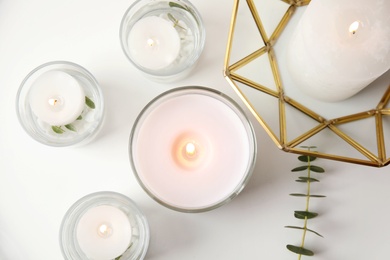 Flat lay composition with burning aromatic candles and eucalyptus on white table