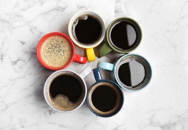 Photo of Many cups with tasty aromatic coffee on marble table, flat lay