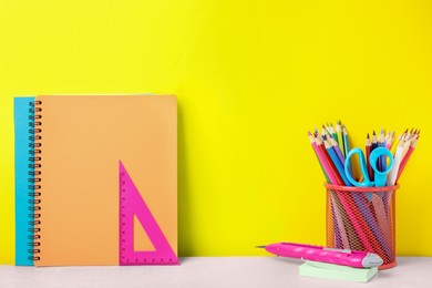 Photo of Different school stationery on white table against yellow background. Back to school
