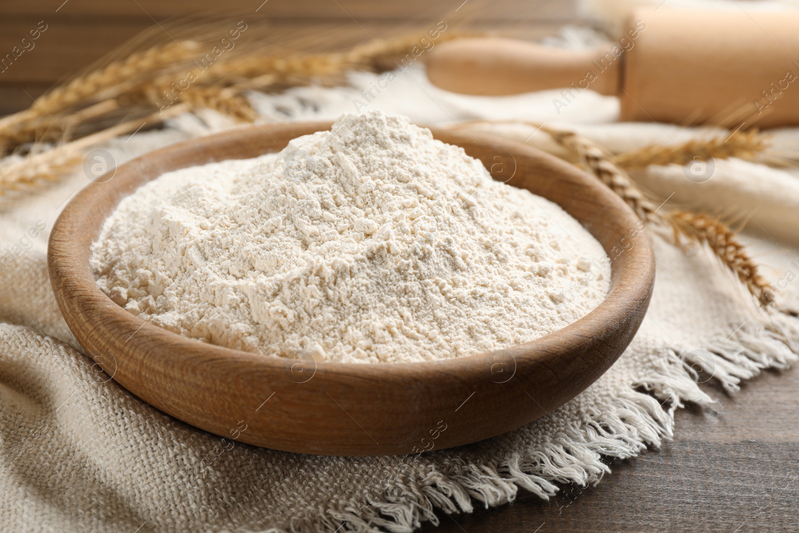 Photo of Bowl with wheat flour on wooden table, closeup
