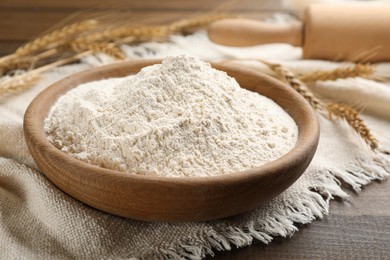 Photo of Bowl with wheat flour on wooden table, closeup