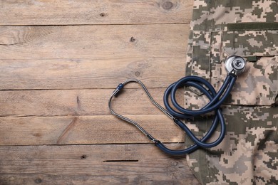 Photo of Stethoscope and military uniform on wooden background, flat lay. Space for text