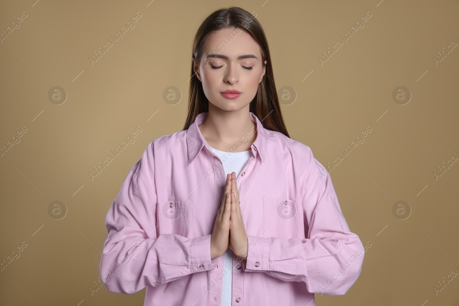 Photo of Woman with clasped hands praying on beige background