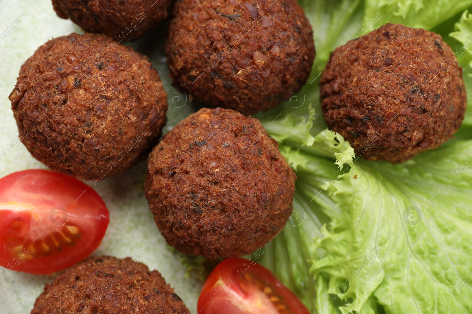 Photo of Delicious falafel balls, tomatoes and lettuce on plate, top view. Vegan meat products