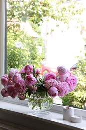Beautiful pink peonies in vase on window sill, space for text. Interior design