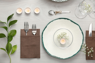 Elegant table setting with green plants on white wooden background, flat lay