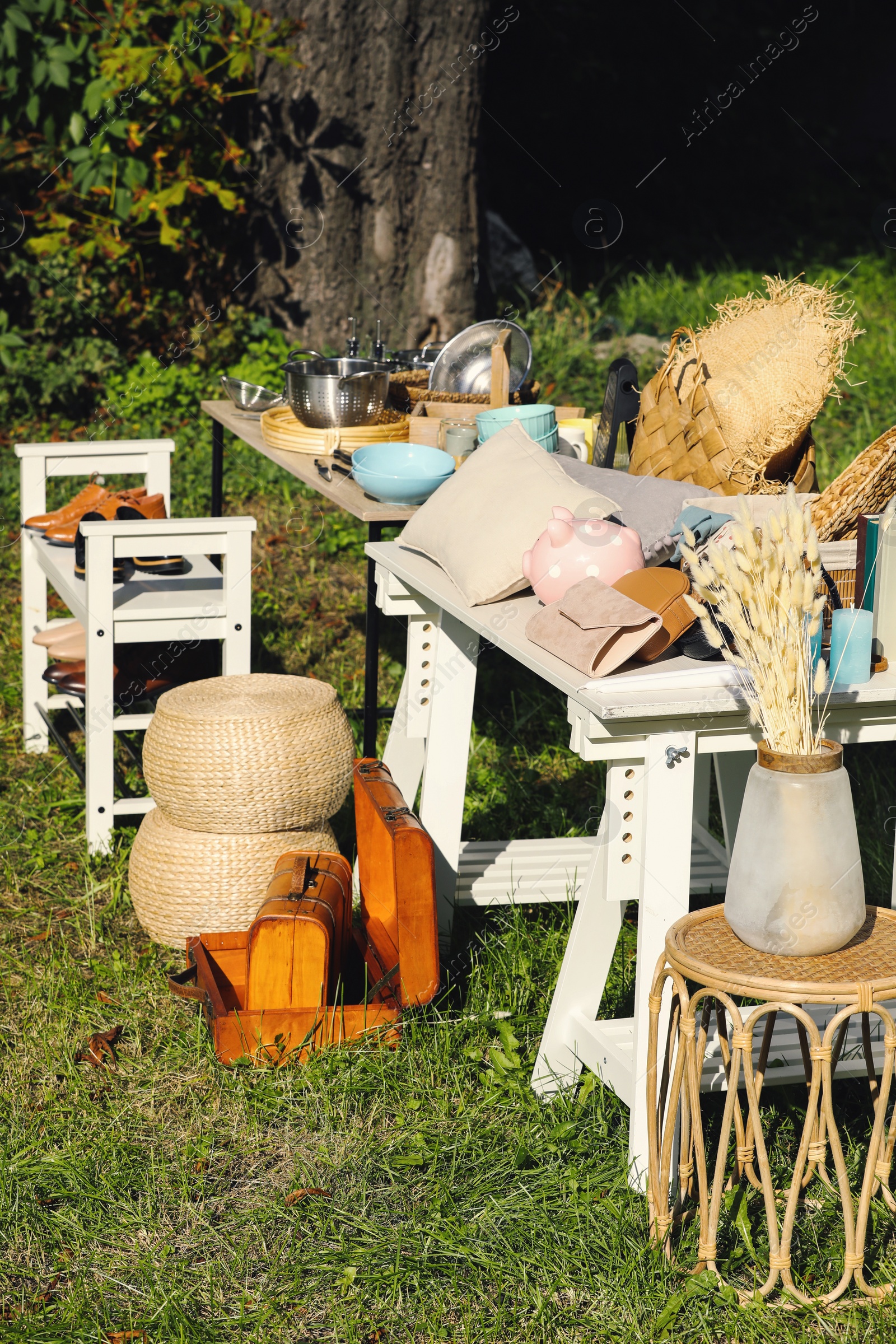 Photo of Small tables with many different items on garage sale outdoors