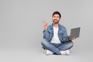 Photo of Happy man with laptop on light grey background. Space for text