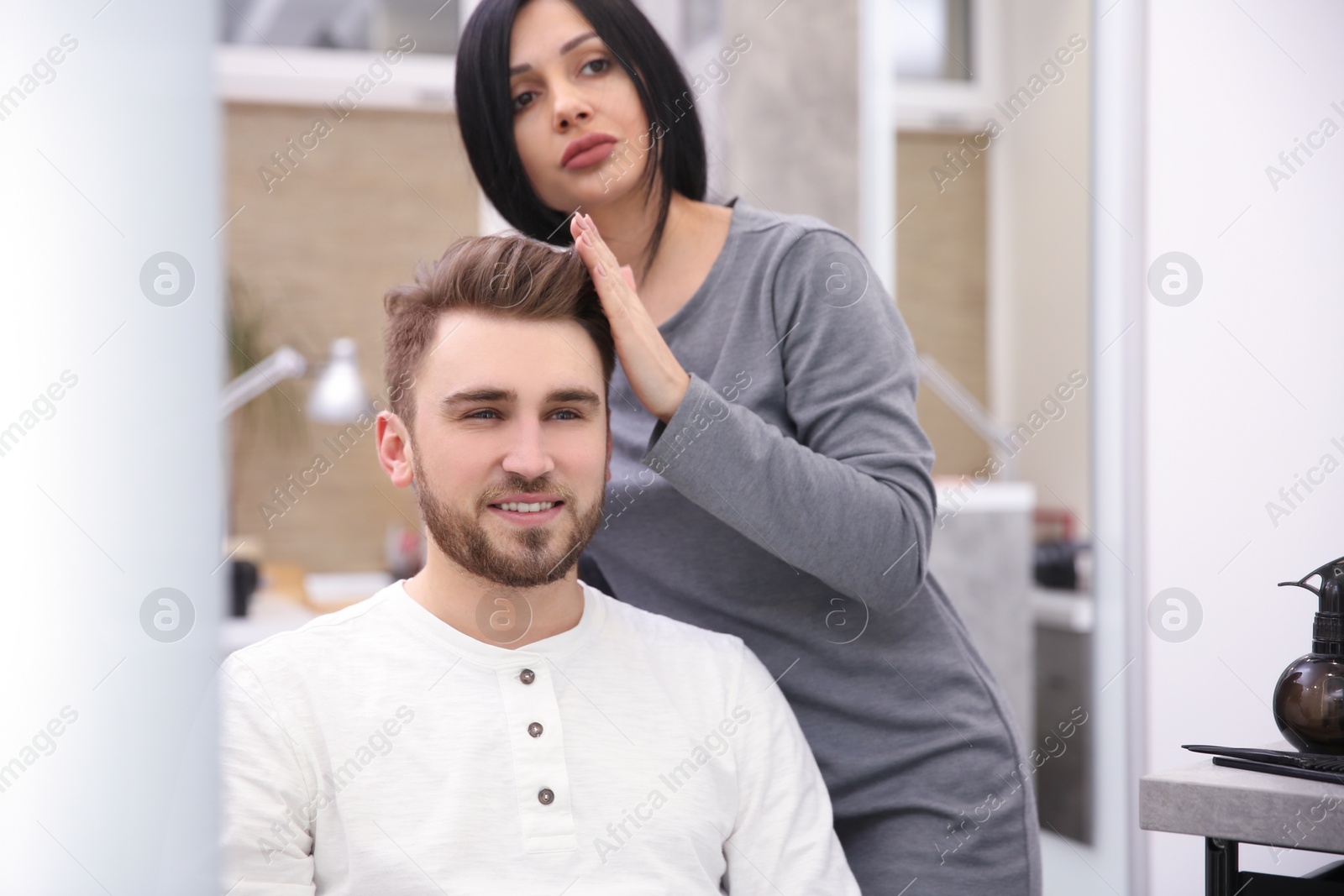 Photo of Professional female hairdresser working with client in salon