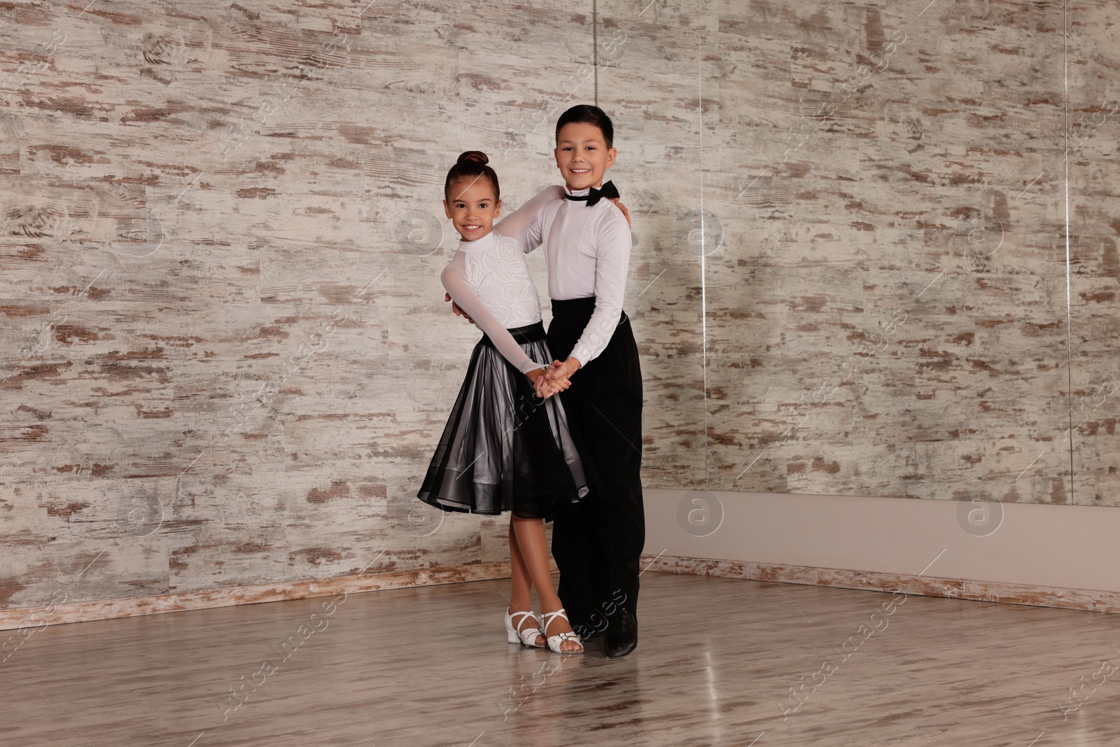 Photo of Beautifully dressed couple of kids dancing together in studio