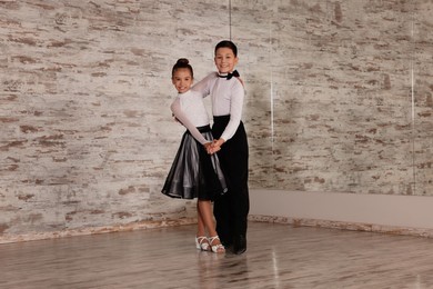 Beautifully dressed couple of kids dancing together in studio