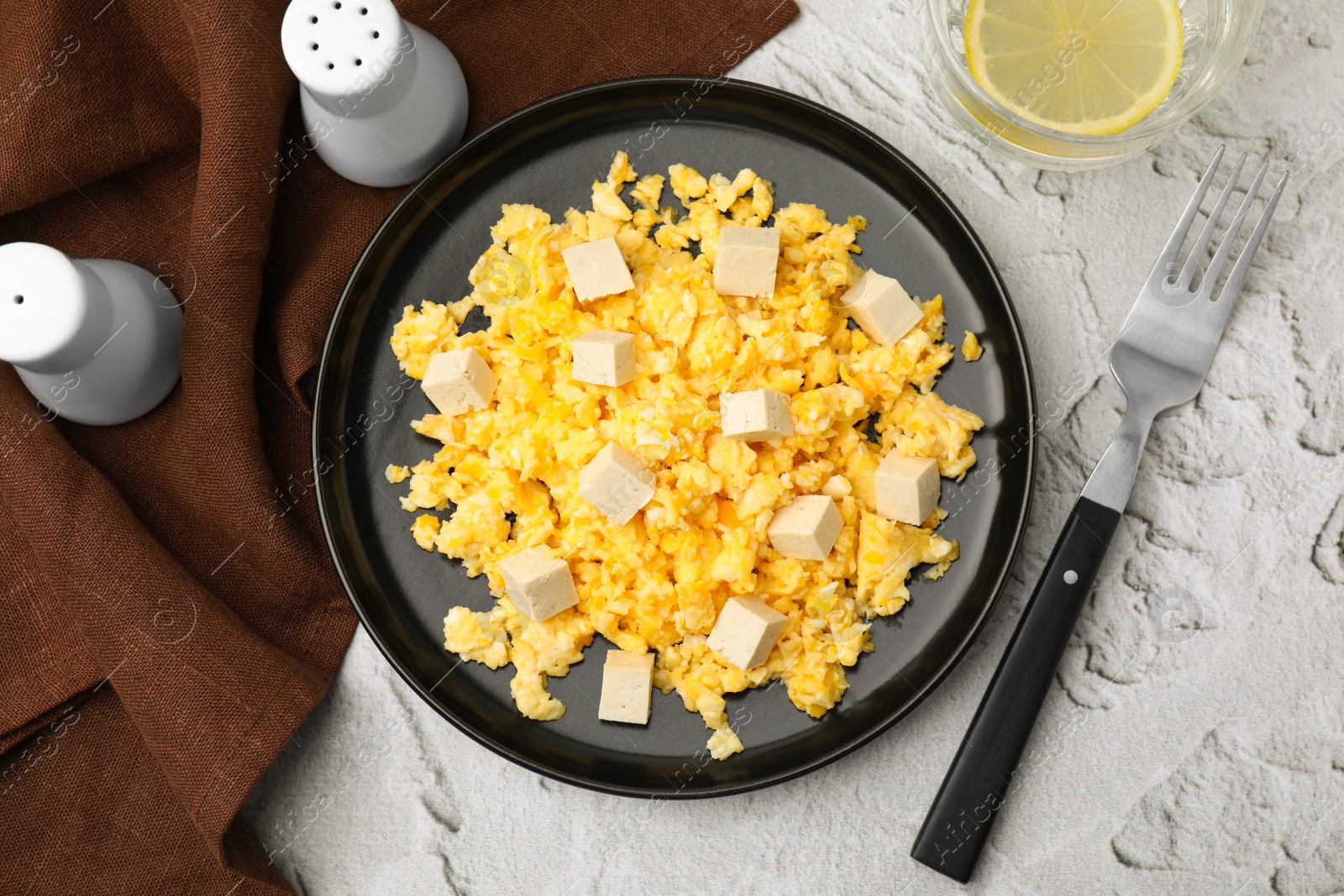 Photo of Plate with delicious scrambled eggs and tofu on white textured table, flat lay