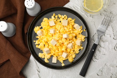 Plate with delicious scrambled eggs and tofu on white textured table, flat lay