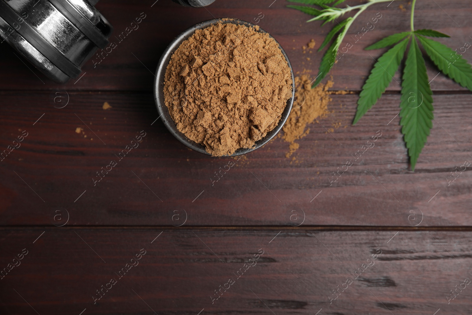 Photo of Hemp protein powder, fresh leaves and dumbbell on wooden table, flat lay. Space for text