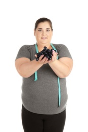 Photo of Overweight woman with grapes and measuring tape on white background