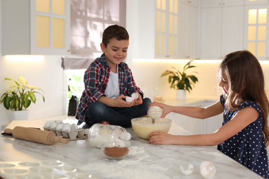 Photo of Cute little children cooking dough in kitchen at home