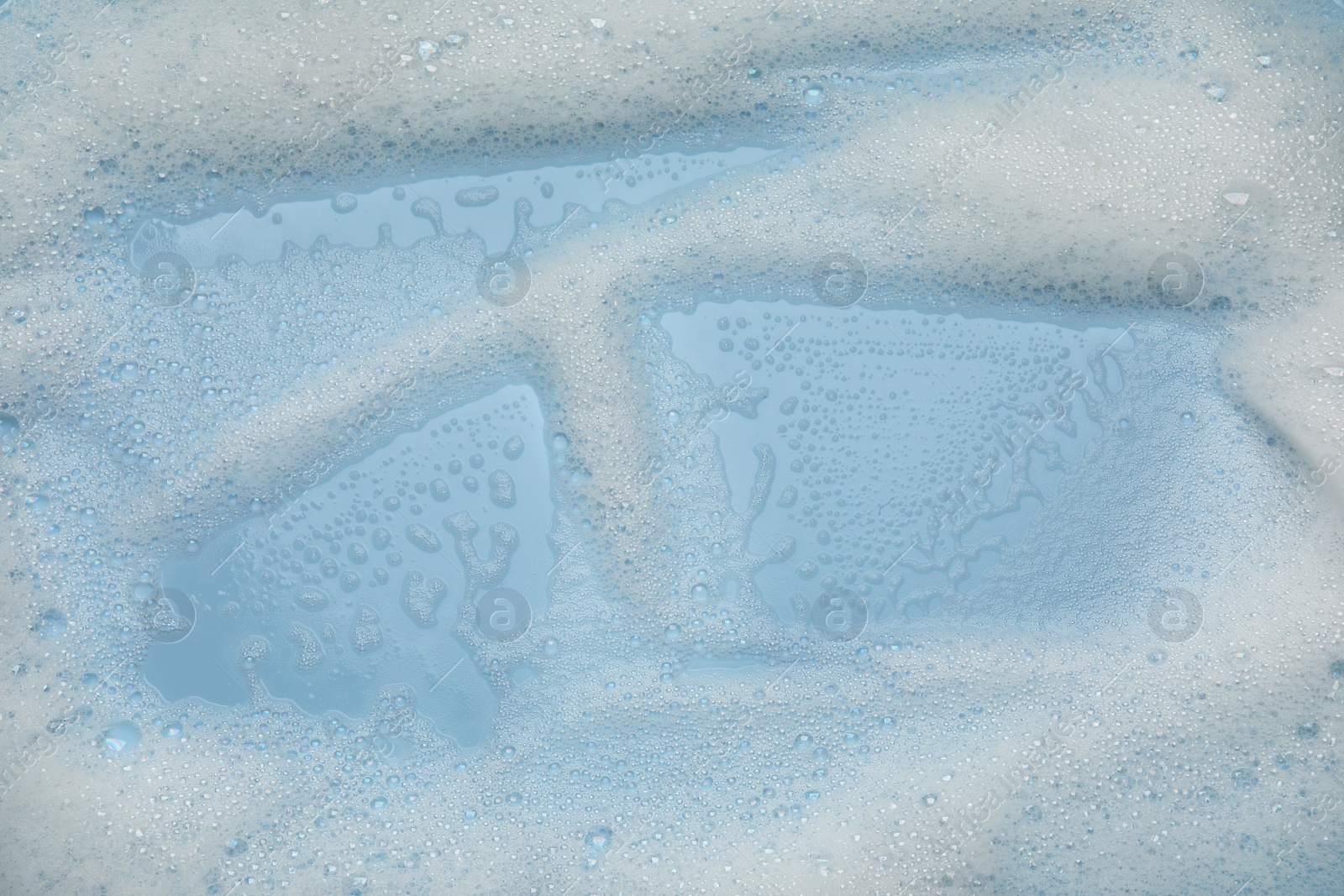 Photo of White washing foam on light blue background, top view