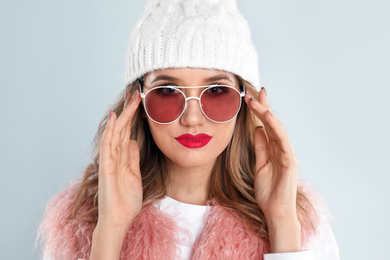 Photo of Young woman wearing stylish sunglasses on light grey background