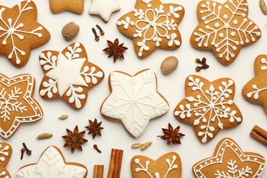 Tasty Christmas cookies with icing and spices on white background, flat lay