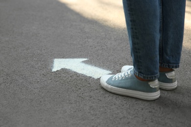 Photo of Person standing near arrow on asphalt, closeup