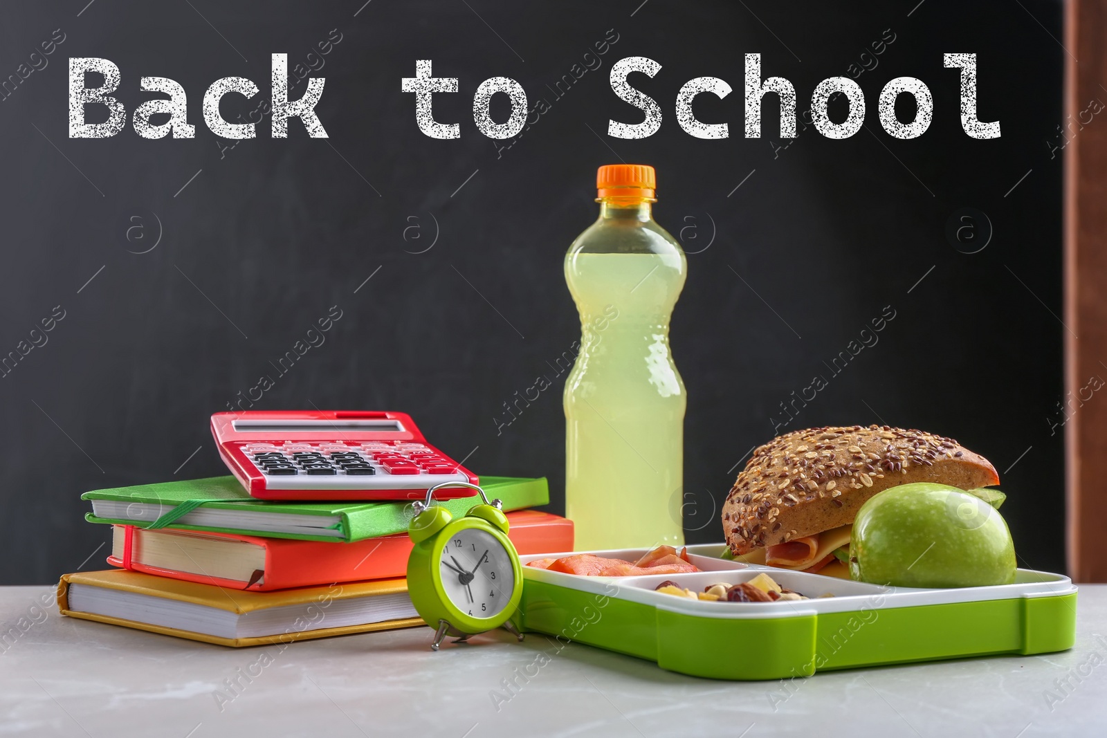 Image of Composition with lunch box and food on table near blackboard