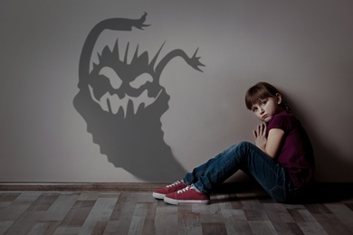 Shadow of monster on wall and scared little girl in room