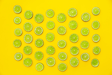 Slices of fresh juicy limes on yellow background, flat lay