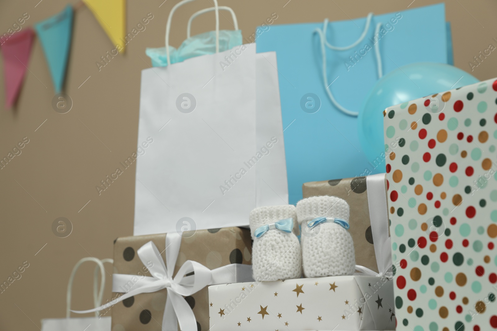 Photo of Baby shower party. Booties, many gift boxes and bags indoors