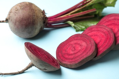 Whole and cut fresh red beets on light blue background, closeup