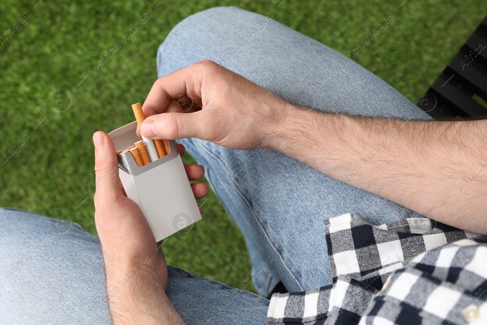 Photo of Man taking cigarette from pack outdoors, above view