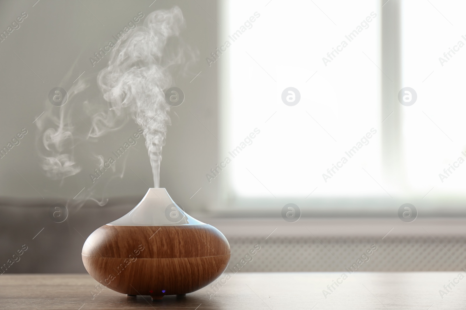 Photo of Modern aroma lamp on table against blurred background with space for text