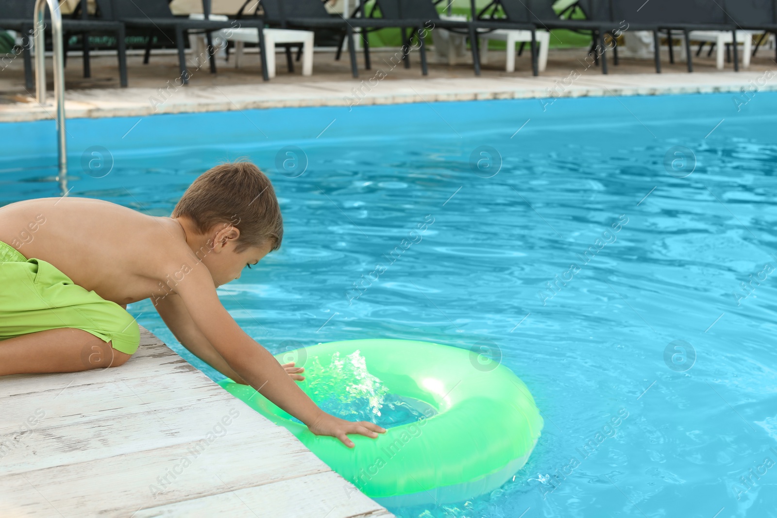 Photo of Little child reaching for inflatable ring in outdoor swimming pool. Dangerous situation