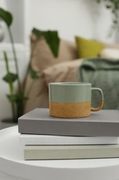 Cup and books on white table in stylish room