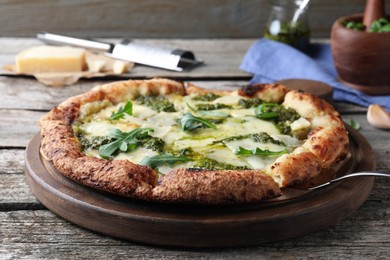 Photo of Delicious pizza with pesto, cheese and arugula on wooden table
