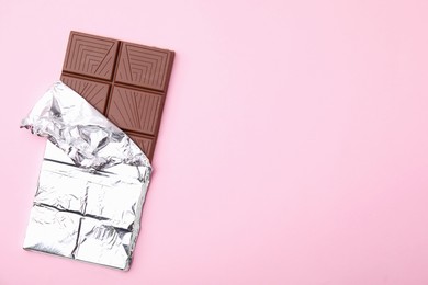 Tasty chocolate bar on pink background, top view. Space for text