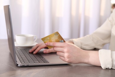 Photo of Online payment. Woman with laptop and credit card at grey table, closeup