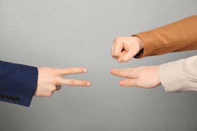 Photo of People playing rock, paper and scissors on grey background, closeup