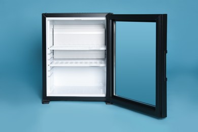 Photo of Empty mini bar with open glass door on turquoise background