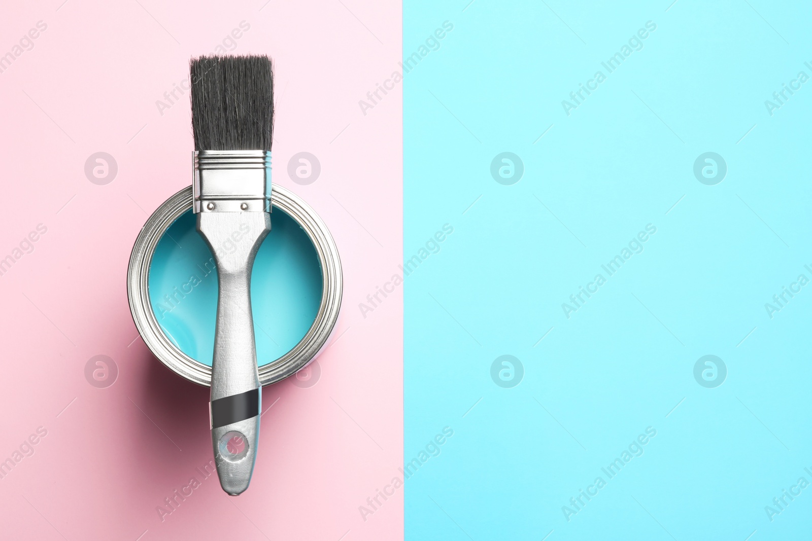 Photo of Open paint can with brush and space for text on color background, top view