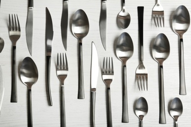 Forks, knives and spoons on wooden table, top view