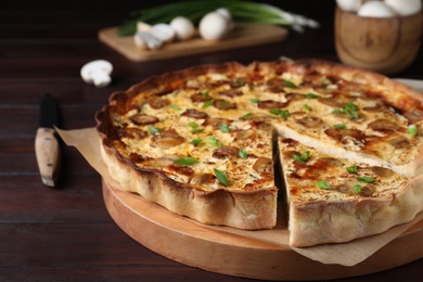 Photo of Delicious pie with mushrooms and cheese on brown wooden table, closeup