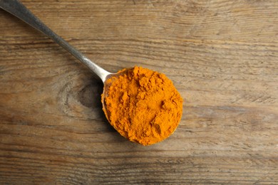 Photo of Spoon with saffron powder on wooden table, top view