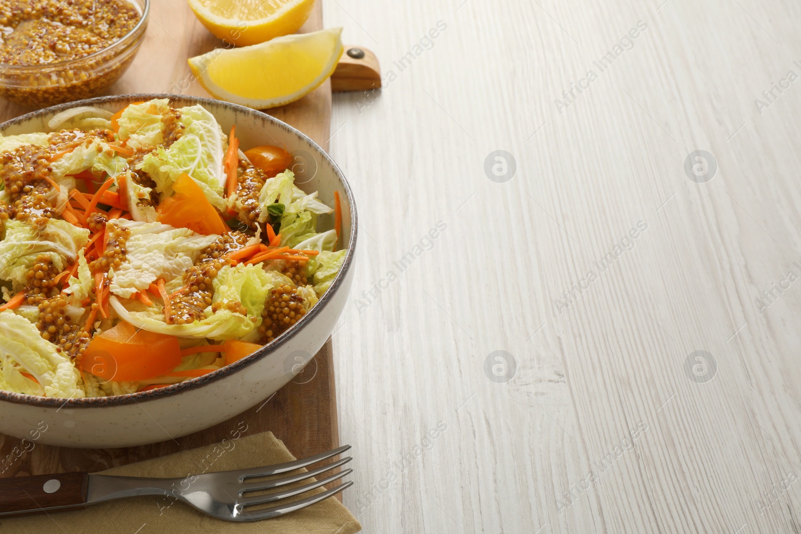 Photo of Delicious salad with Chinese cabbage and mustard seed dressing on white wooden table. Space for text