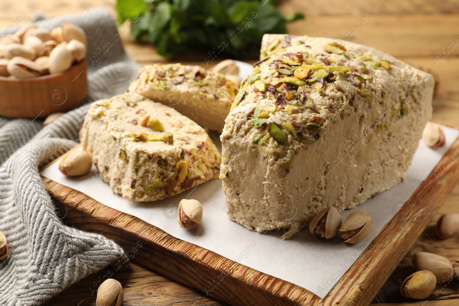 Photo of Tasty halva with pistachios on table, closeup