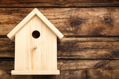 Photo of Beautiful bird house on wooden background, space for text