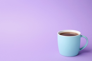 Blue ceramic cup with hot aromatic coffee on color background