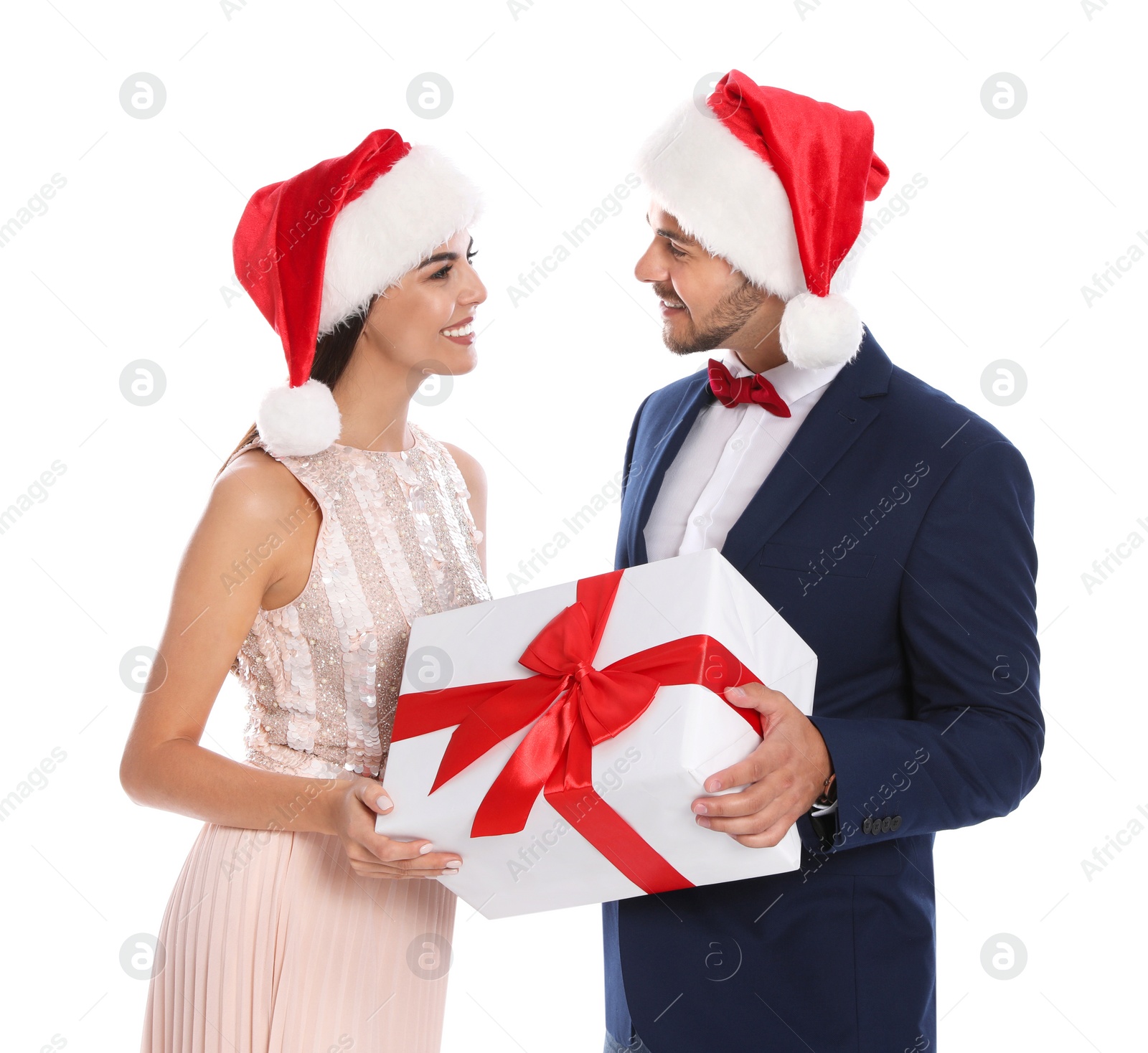 Photo of Lovely young couple in Santa hats with gift box on white background. Christmas celebration