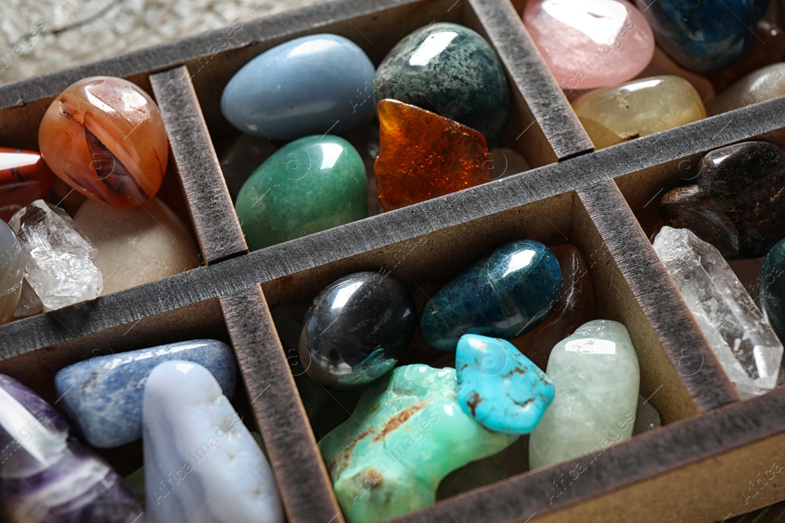 Photo of Box with different beautiful gemstones on table, closeup